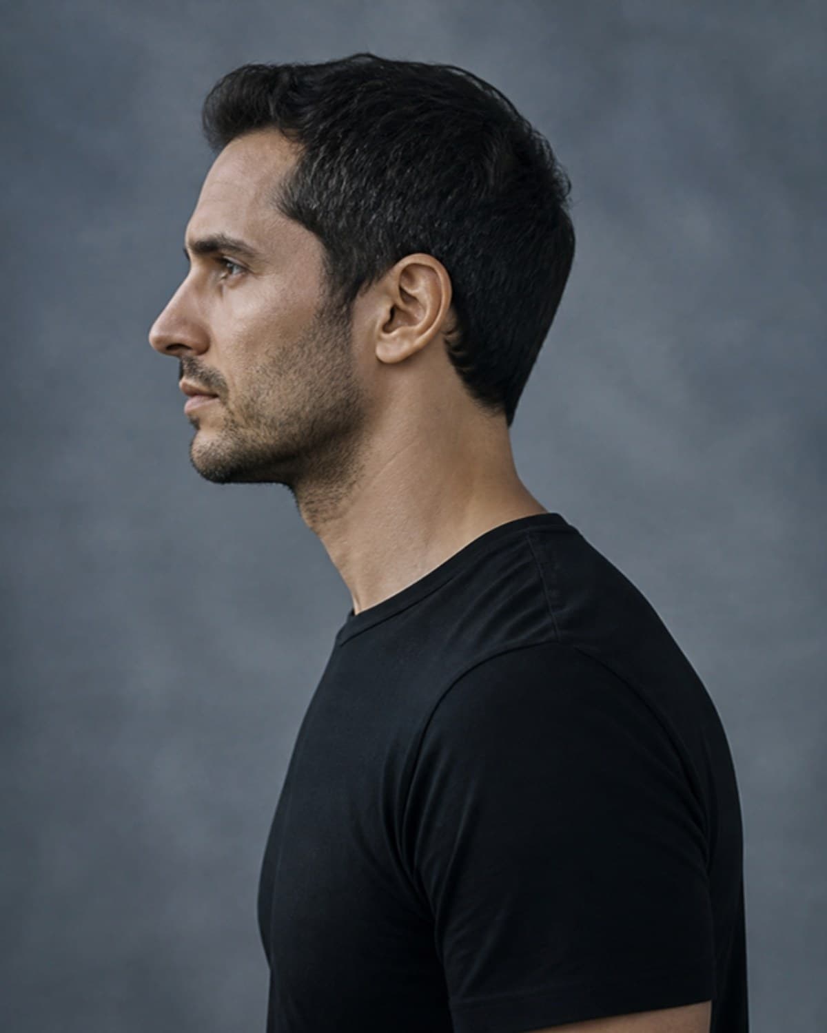 Side profile portrait of a man against a blue-grey backdrop