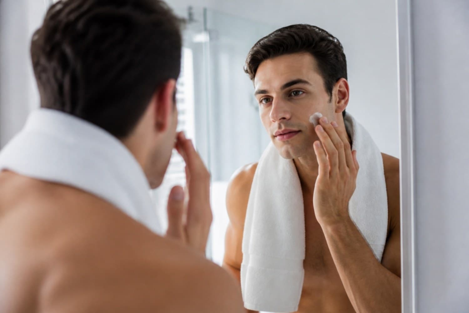 A man applying moisturiser in a bright bathroom
